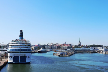 Fototapeta na wymiar Big white ship ferry vacation trip in Tallinn port dock harbor on water. Blue sky and bright day in sea