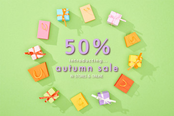 round frame of decorative gift boxes and shopping bags on green background with 50 percent off autumn sale illustration