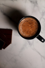 cocoa drink in a blue mug with chocolate on a light background closeup