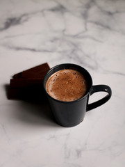 cocoa drink in a blue mug with chocolate on a light background closeup