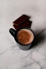 cocoa drink in a blue mug with chocolate on a light background closeup