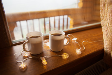 two cups of coffee on the windowsill in a wooden house in the Carpathians
