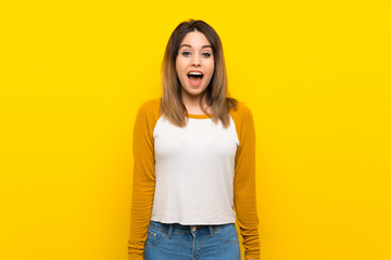 Pretty young woman over isolated yellow wall with surprise facial expression