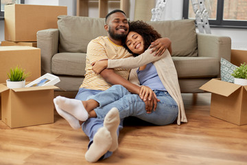 moving, repair and real estate concept - happy african american couple with cardboard boxes hugging at new home