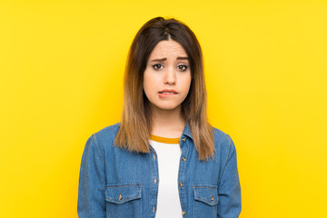 Fototapeta premium Young woman over yellow background having doubts and with confuse face expression