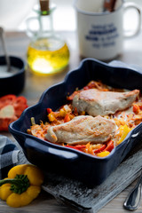 Chicken fillet baked with peppers in a blue ceramic dish on a wooden table