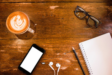 Blank notebook and smart phone white screen with coffee on wooden table