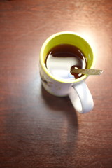 Mug of black coffee with a spoon on the table