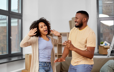 moving, repair and real estate concept - happy african american couple dancing at new home