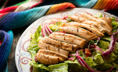 Mexican caesar salad with grilled chicken, romaine lettuce, croutons, dressing, and parmesan cheese. 