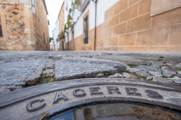 manhole cover in the streets with inscription caceres in the old eponymous historic capital of the...