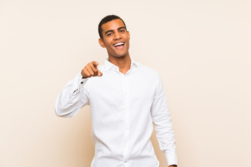 Young handsome brunette man over isolated background surprised and pointing front