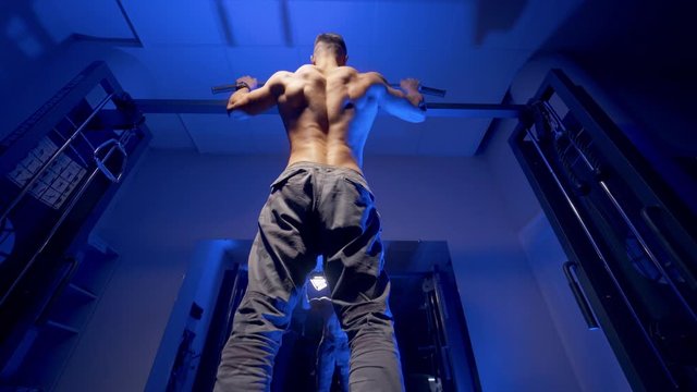Man doing pull up exercise. Young man doing pull ups on horizontal bar indoors
