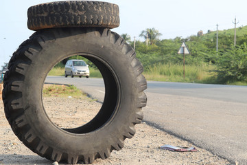 Small Tyre Mounted on Big Tyre with Car in View for Tyre Puncture Service