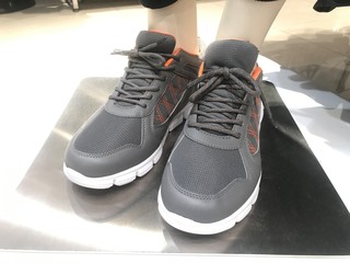 Grey color pair of Sneakers wore by a garments toy for demo on a stainless steel and fixed rigid...