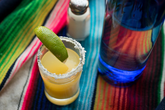 Margarita cocktail with tequila, orange liqueur, lime juice, with a salted rim, and garnished with a lime wedge.