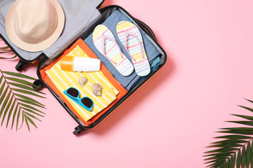 Flat lay composition with open suitcase and space for text on pink background