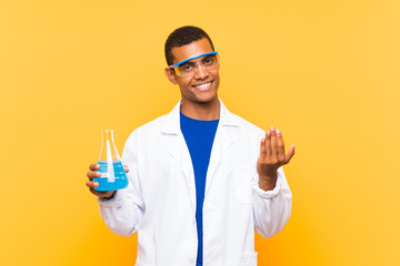Scientific man holding a laboratory flask over isolated background inviting to come with hand....