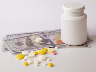 Healthcare savings and expencive medicine concept. Pills scattered over dollar banknotes. Bottle of pills and money