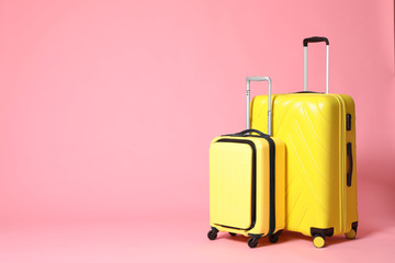 Stylish yellow suitcases on pink background. Space for text