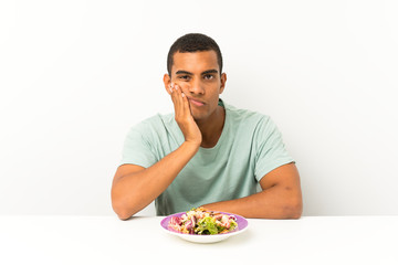 Young handsome man with salad in a table unhappy and frustrated