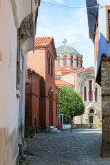 Fototapeta na wymiar Cosy narrow street with old houses and church on the background in Edessa greece