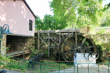 View of old water mill with green trees on the background