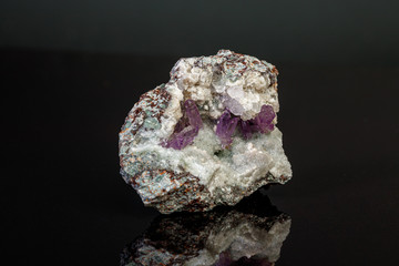 macro mineral amethyst stone in rock on a black background