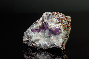 macro mineral amethyst stone in rock on a black background