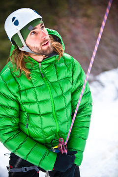 Closeup detail shot of a down coat and a man, , belaying a climber.