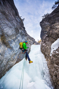 A man  rapells down a icy gully after climbing  Rainbow Serpent (100m WI6) in the Recital Hall, a beautiful rock ampitheatre in the Ghosts in Alberta, Canada. The approach to get to Rainbow Serpent involves climbing numerous moderate pitches of ice that are rapelled down during the descent.