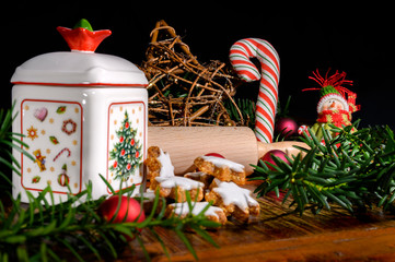 Christmas scene with cinnamon stars, rolling pin, a ceramic biscuit tin and other christmas decoration on an old wooden table.