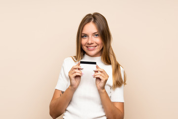 Young blonde woman over isolated background holding a credit card