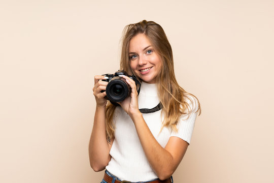 Young blonde woman over isolated background with a professional camera