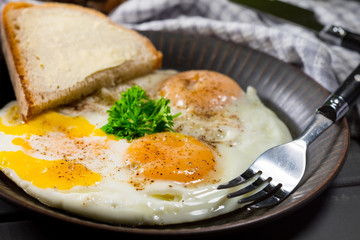 Fried eggs and bread for breakfast on a gray background.