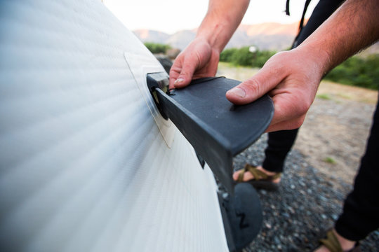 A man puts the fin in his stand up paddle board during an early morning summer SUP session in southeast Washington.