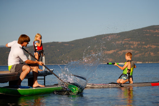 A girl prepares to jump off a dock into in Lake Pend Oreille next to her dad and brother in north Idaho in summer.