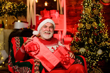 Obraz na płótnie Canvas Traditions concept. Legend about Santa Claus. Bearded senior man Santa Claus. Merry christmas. Elderly grandpa at home. Delivering gifts. Presents for family. Santa Claus relaxing in arm chair