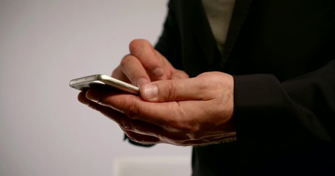 man is browsing social neat and email by cell phone, touching screen by fingers, closeup of hands