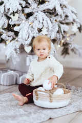 Little girl near the Christmas tree. Christmas morning, searching for gifts.