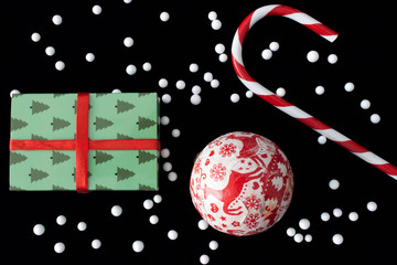 Christmas decoration with candy stick, handmade ornament ball and gift box on black background.