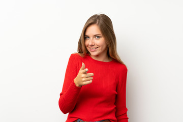 Young blonde woman with red sweater over isolated white background points finger at you