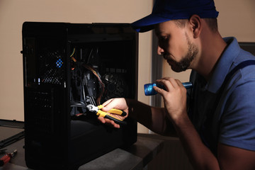 Repairman with flashlight fixing system unit indoors - obrazy, fototapety, plakaty