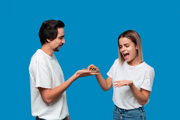 Boyfriend giving present to his girlfriend isolated over blue background.