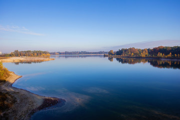 Dutch landscape with calm river and blue sky, autumn season colorful yellow and orange trees, top view in the Netherlands