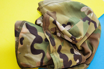 Camo balaclava mask on yellow and blue background.