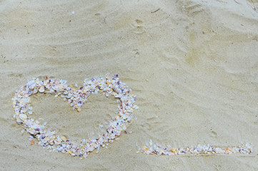 The heart on the sand is made of seashells as a symbol of love