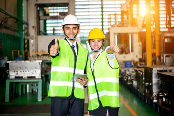 Fototapeta na wymiar Businessmen or male engineers and female engineers are working in industrial plants that have machines and injection molds, with tablets used to control technology.