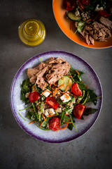 Salad with tuna, tomato, carrot and mustard vinaigrette in a purple rimmed salad bowl