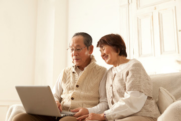 PCを操作する仲の良いシニア夫婦